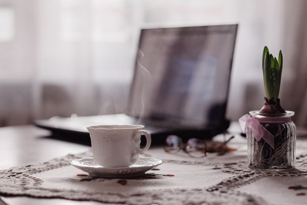 Xícara de café e um notebook sobre a mesa, representando uma pausa no trabalho